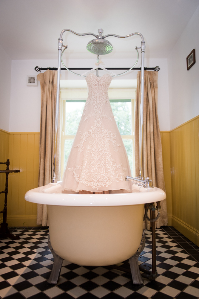 Brides wedding dress hanging over a bathtub at Brooklodge
