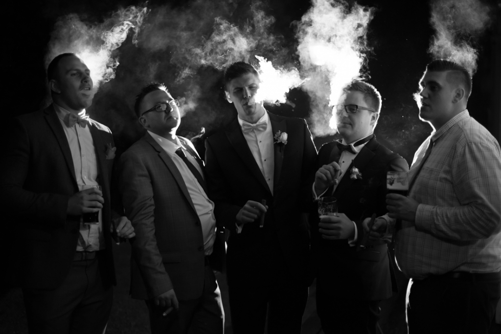 Groom and friends smoking cigars at night time
