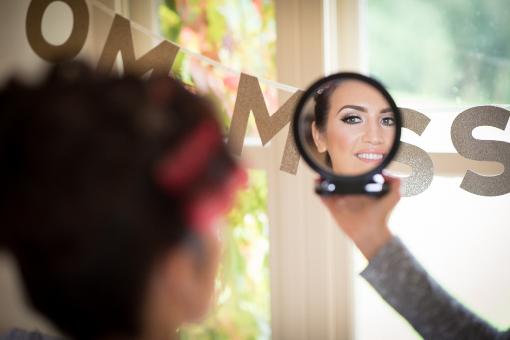 Bride looking into the mirror checking her makeup