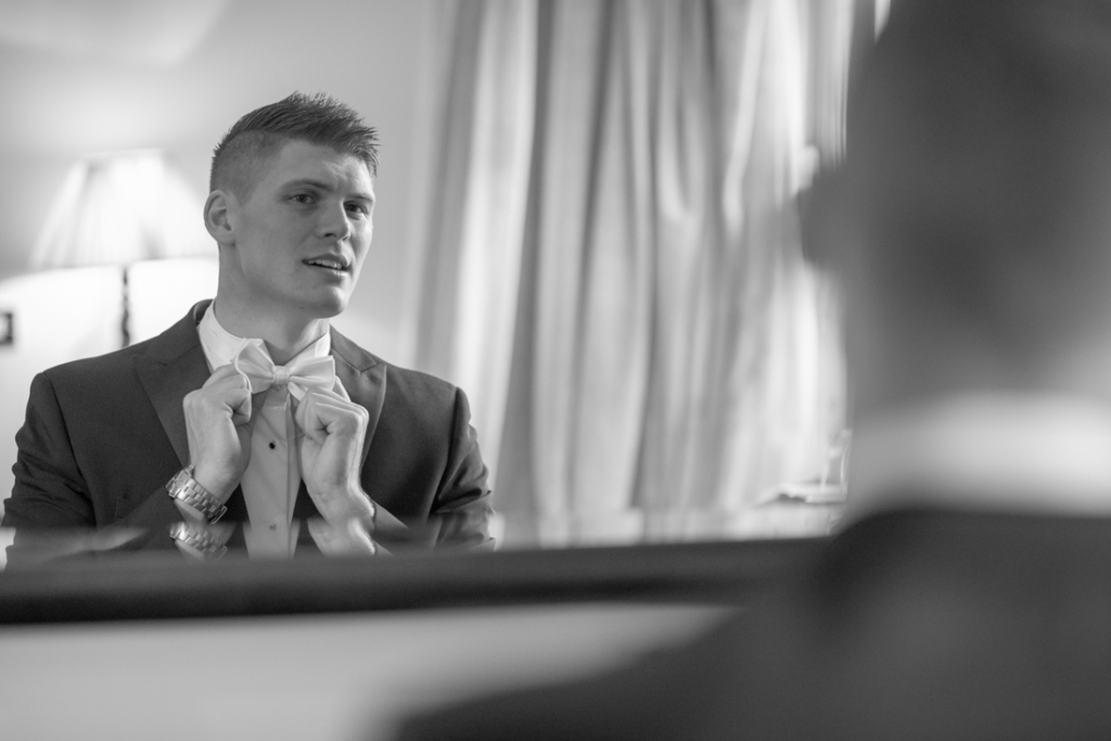 Groom putting on his bow tie for his Brooklodge wedding