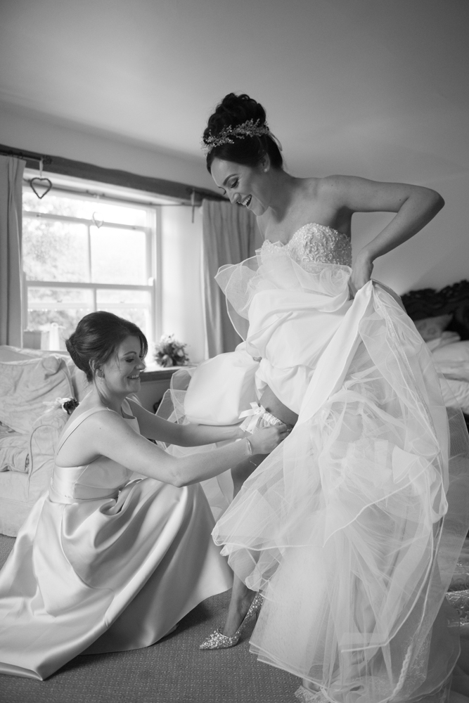 Bridesmaid putting on the brides garter 