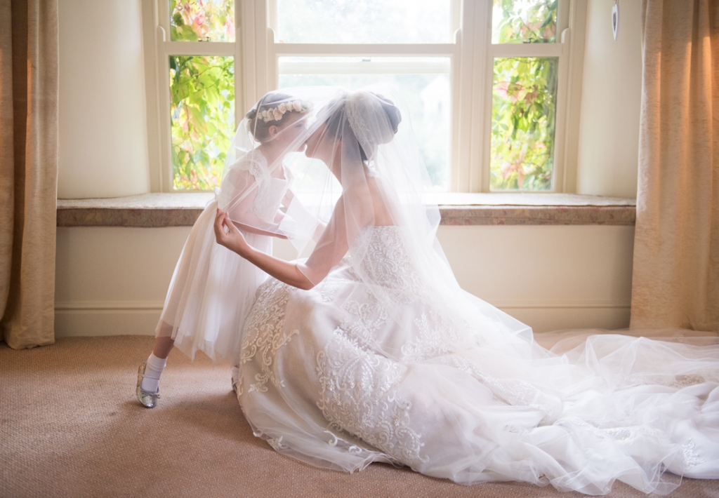 Bride and flower girl kissing under Brides veil