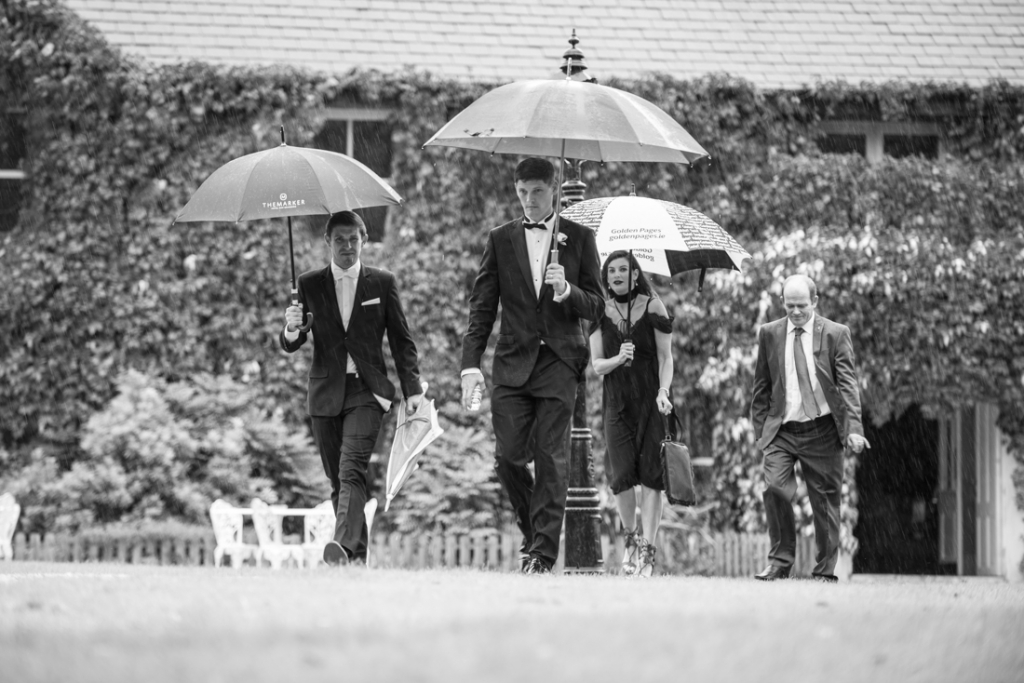 Guests holding umbrellas walking to the ceremony at Brooklodge