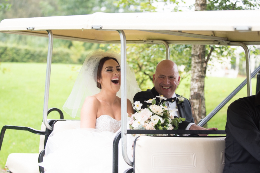 Bride and her dad laughing in the back of a golf buggy