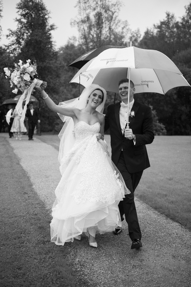 Bride and groom walking under an umbrella at their Brooklodge wedding