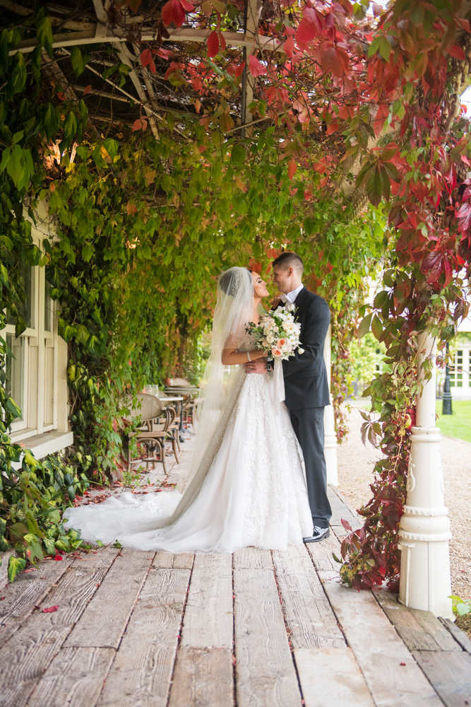 Bride and Groom standing under the red and green leaves on the boardwalk at Brooklodge