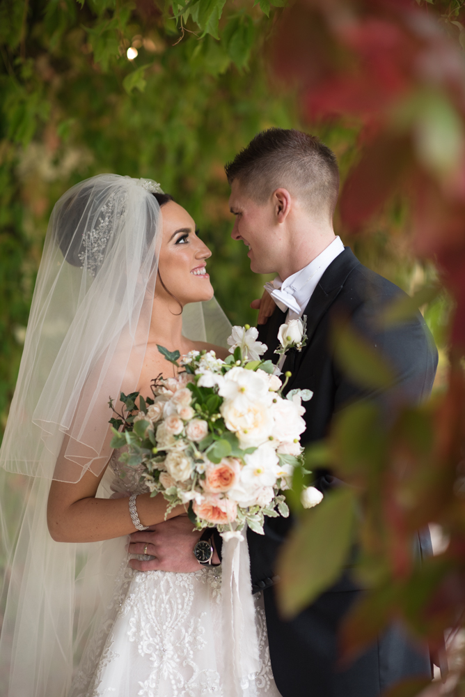 Bride and Groom smiling and looking at each other under the autumn leaves