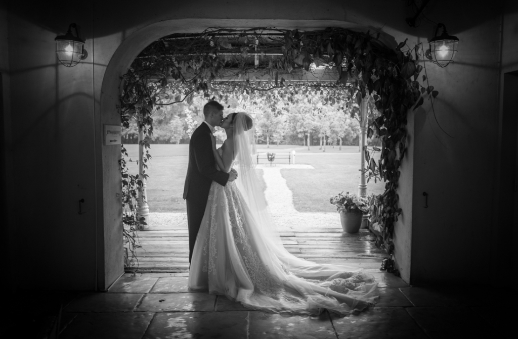 Bride and groom kissing under the arch at Brooklodge