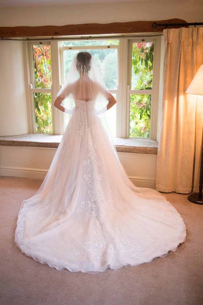 Bride standing looking out the window on her wedding day