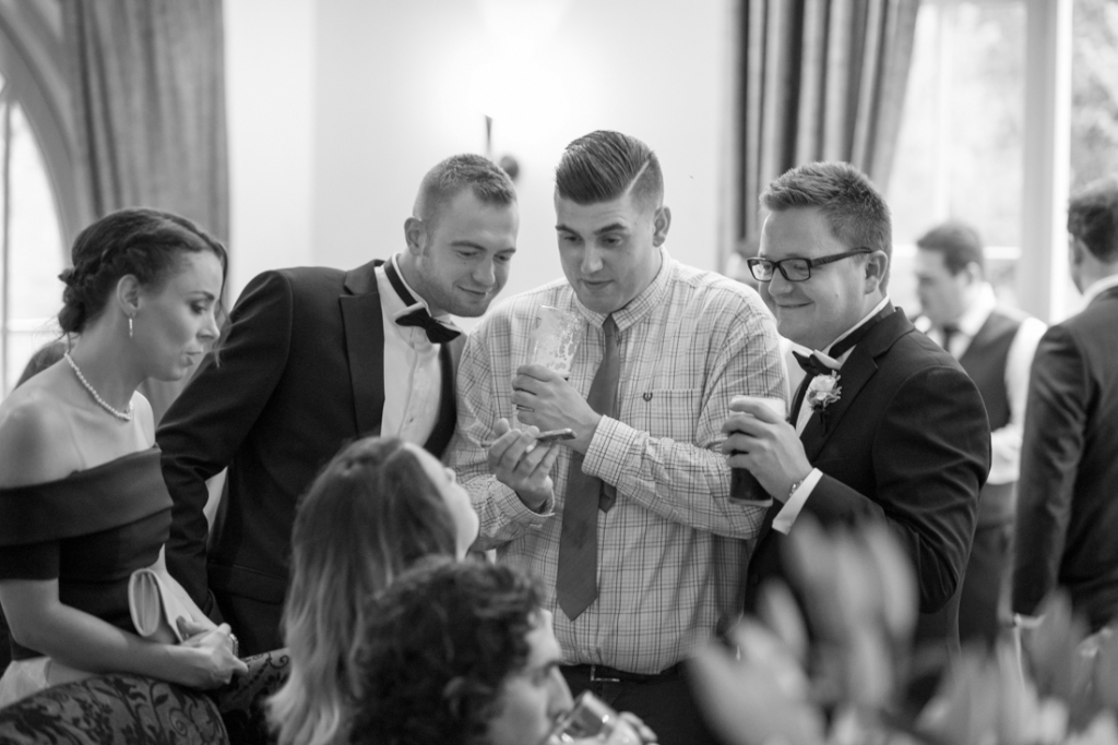 Wedding guests watching a football match on their phone together