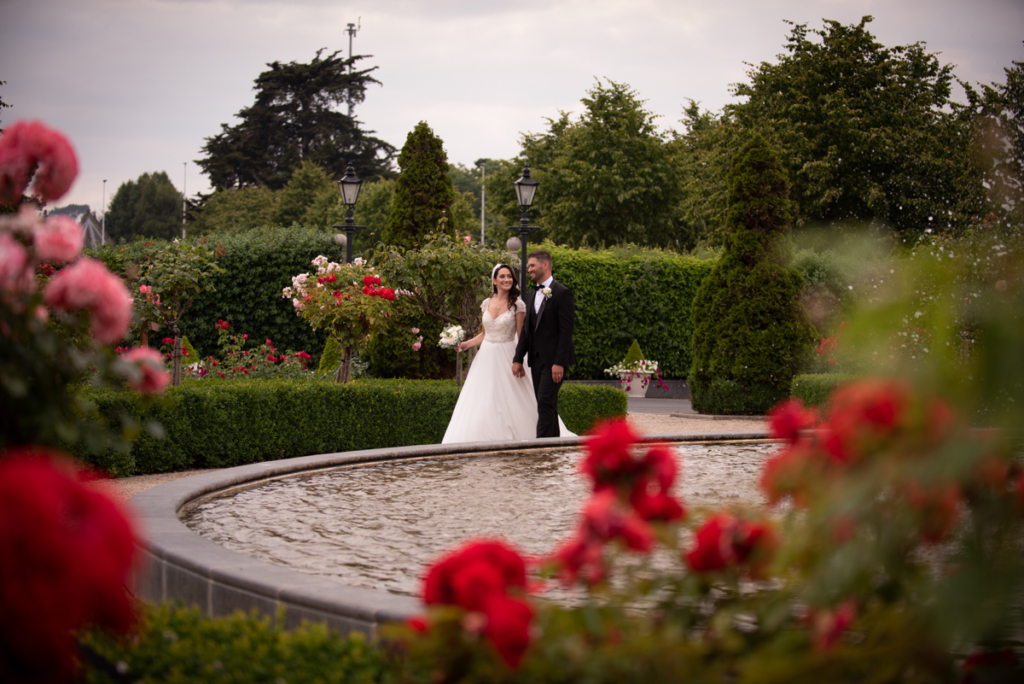 bride and groom walking through rose garden