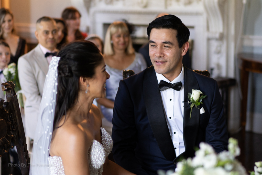 James Stewart and Sarah Roberts looking and smiling at each other while sitting at their wedding ceremony