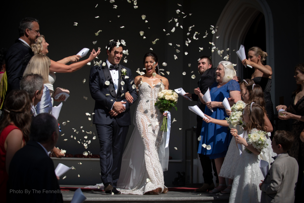 Sarah Roberts and James Stewart outside Luttrellstown Castle with their guests throwing confetti over them