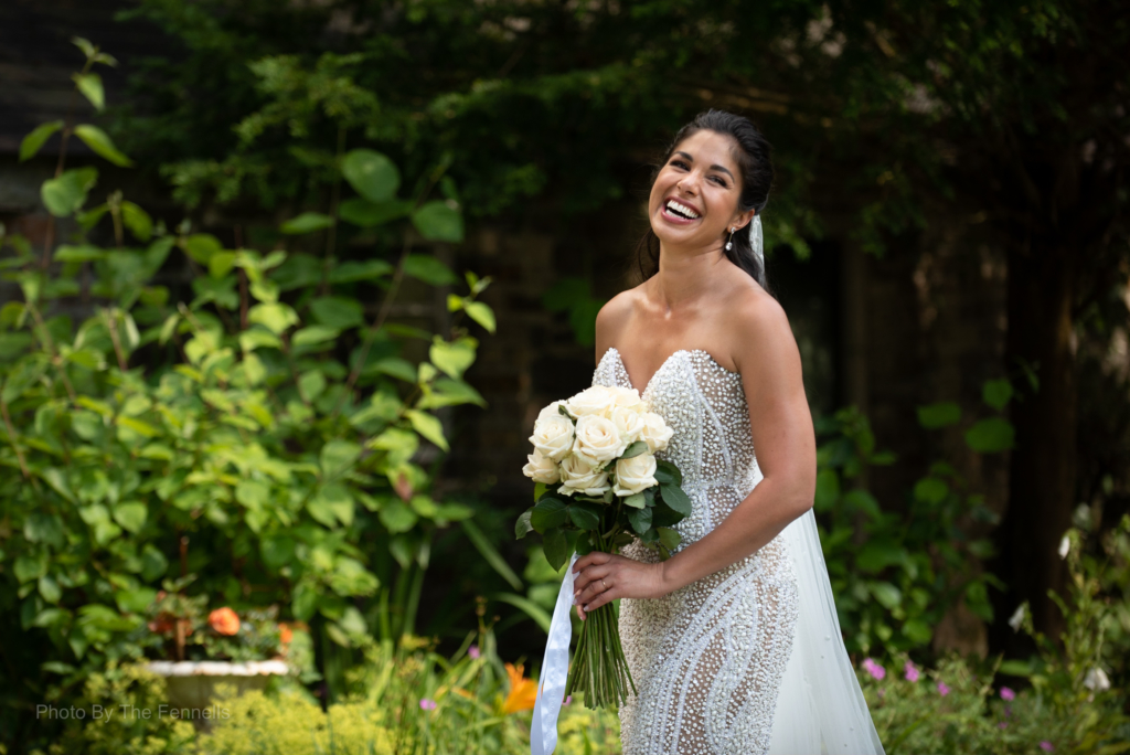 Sarah Roberts holding her wedding bouquet and laughing in the gardens at Luttrellstown Castle