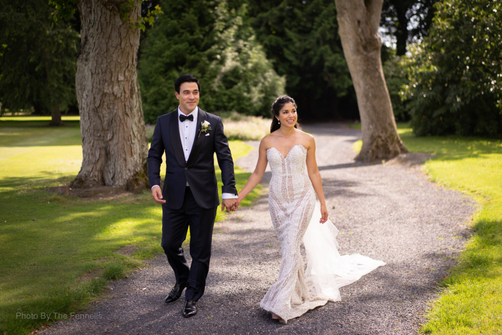 James Stewart and Sarah Roberts walking and surrounded by trees holding hands on the grounds of Luttrellstown Castle