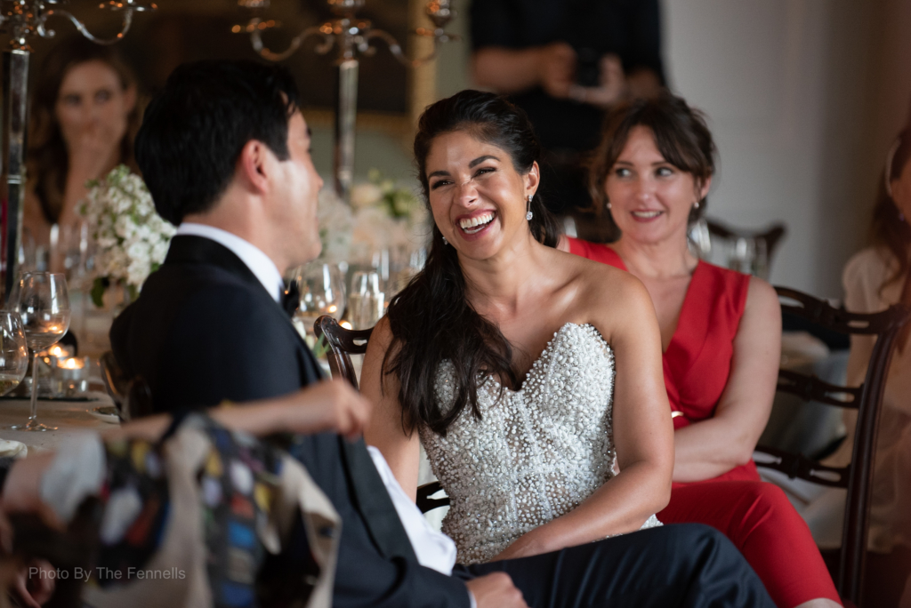 Sarah Roberts and James Stewart laughing together listening to the wedding speeches