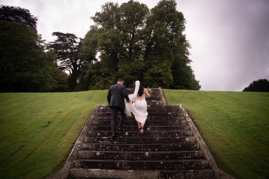 Bride and groom walking up the steps in garden at their castle leslie wedding in ireland