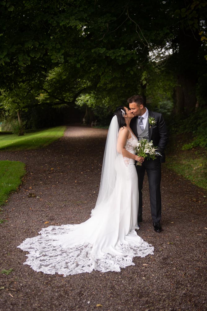 Bride and groom kissing under the trees at castle leslie estate