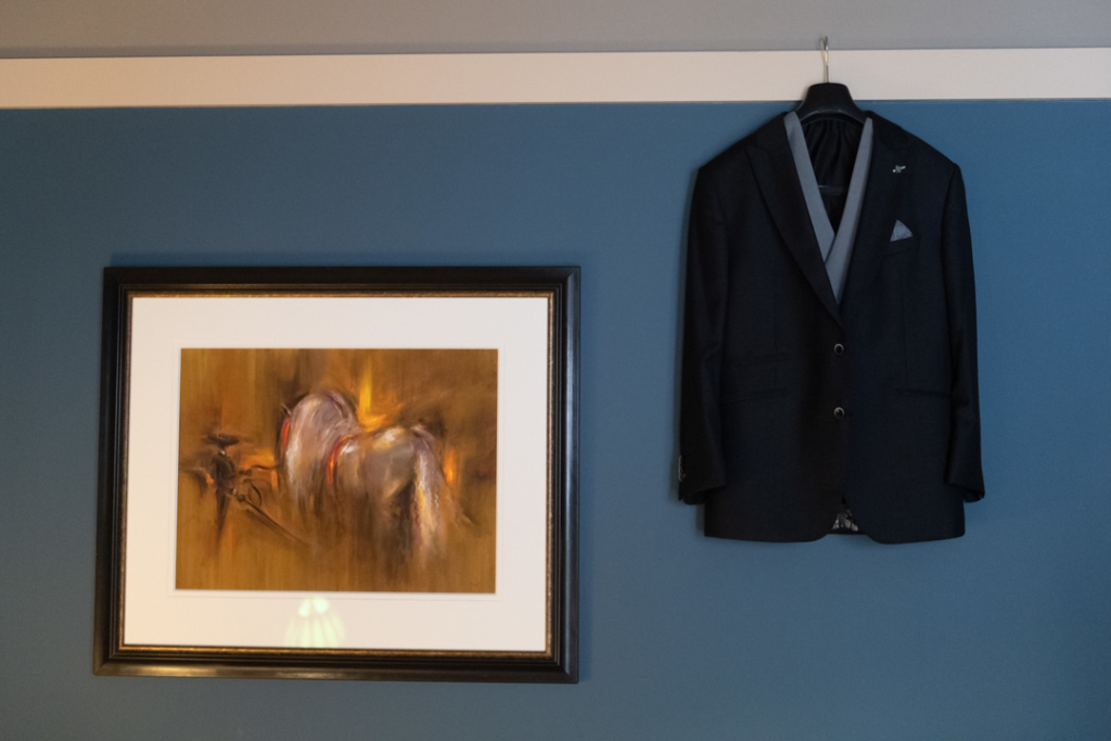Grooms suit hanging up on wall beside picture