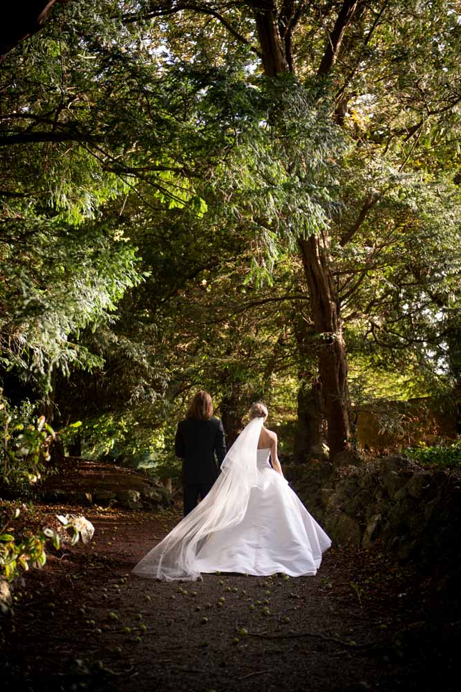 bride and groom walking holding hands through castle forrest