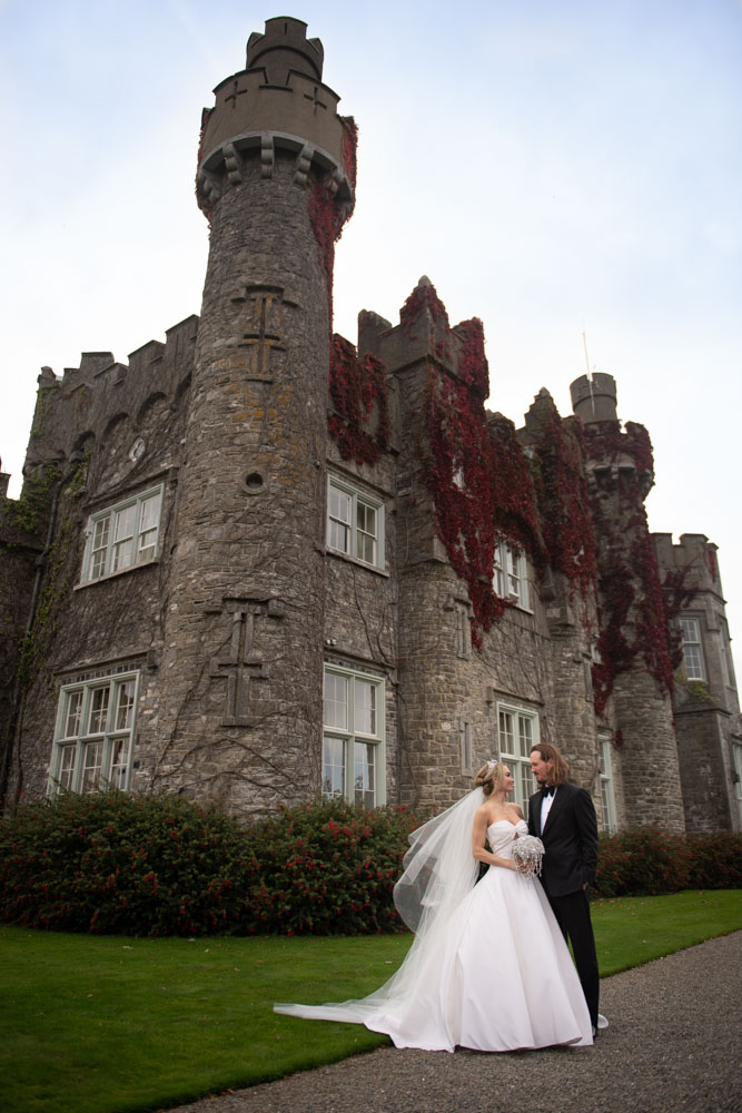 bride and groom standing outside luttrellstown castle tower