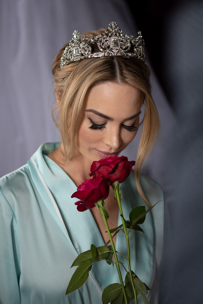 bride wearing crown smelling red rose