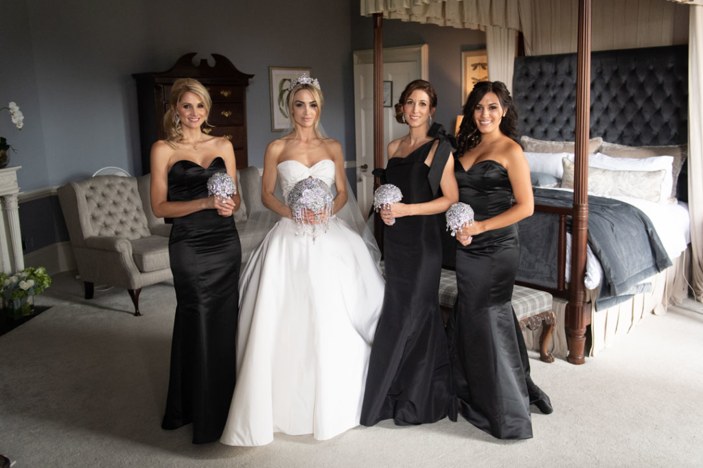 Bride in white and her bridesmaids in black dresses holding diamanté bouquets