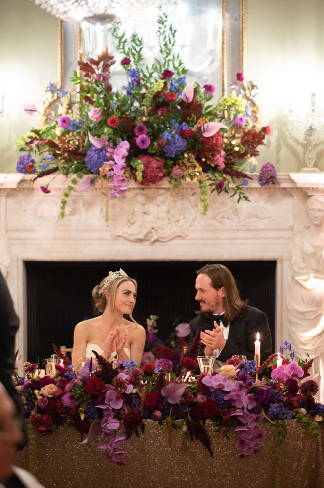 Bride and Groom at top table clapping and looking at each other during speeches