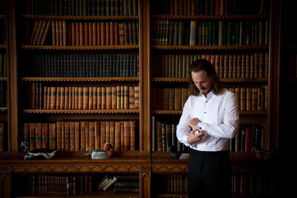 groom in white shirt fixing cufflinks in luttrellstown castle library