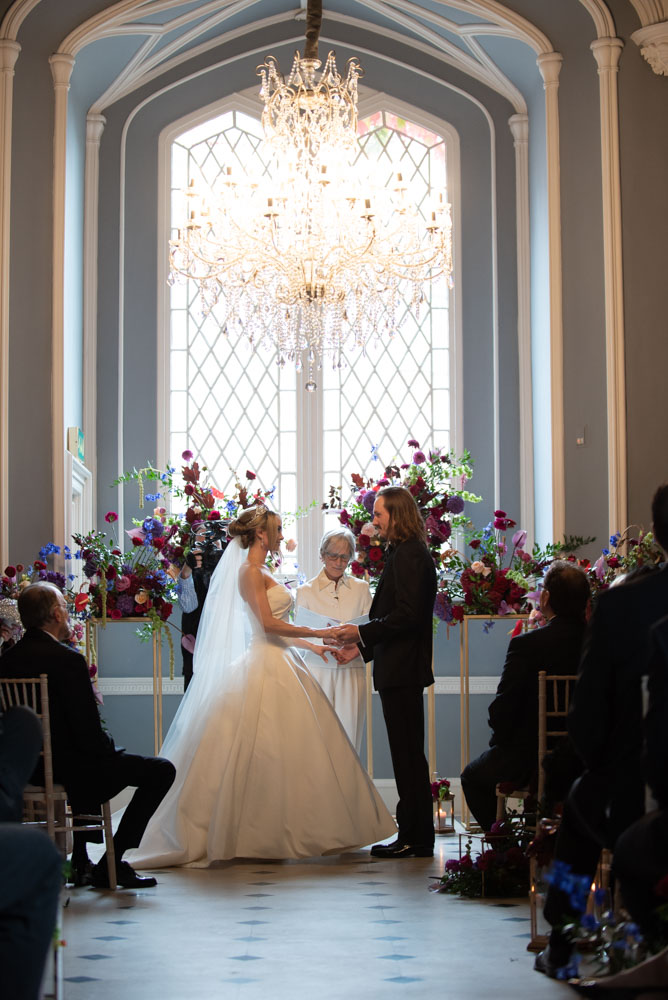 bride and groom saying vows standing under chandelier in luttrellstown castle