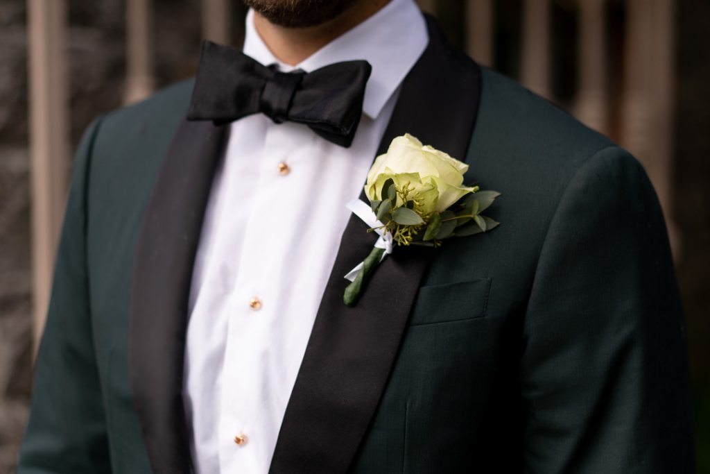 Grooms white rose buttonhole flower on his green suit