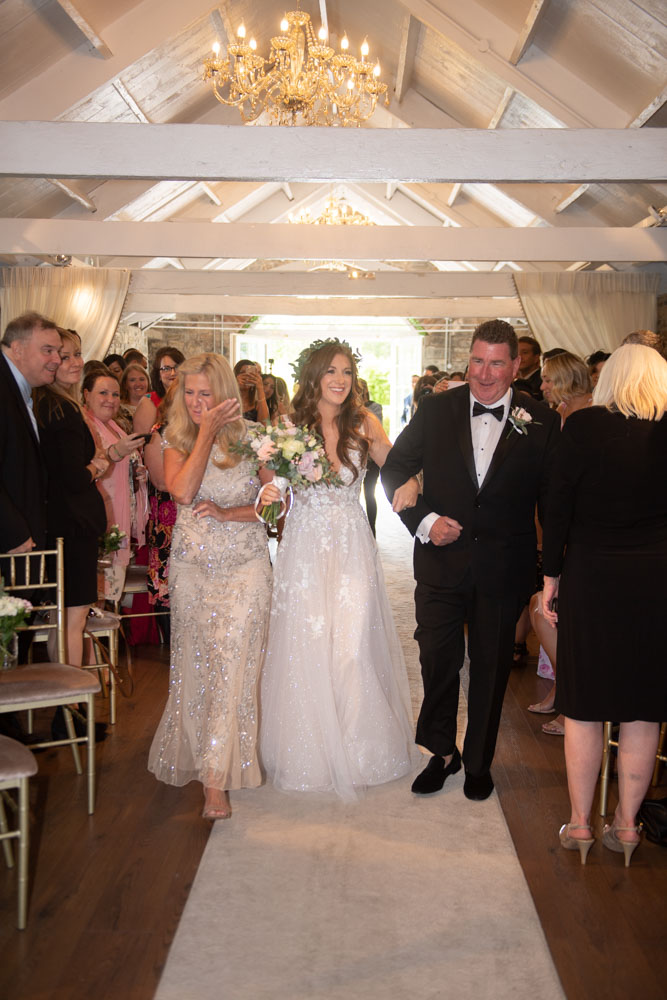 Bride walking up the aisle with her parents in Ballymagarvey