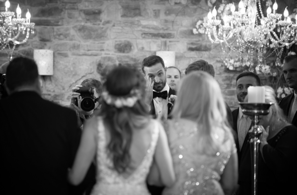 Groom wiping away his tears as he is watching his Bride walk up the aisle