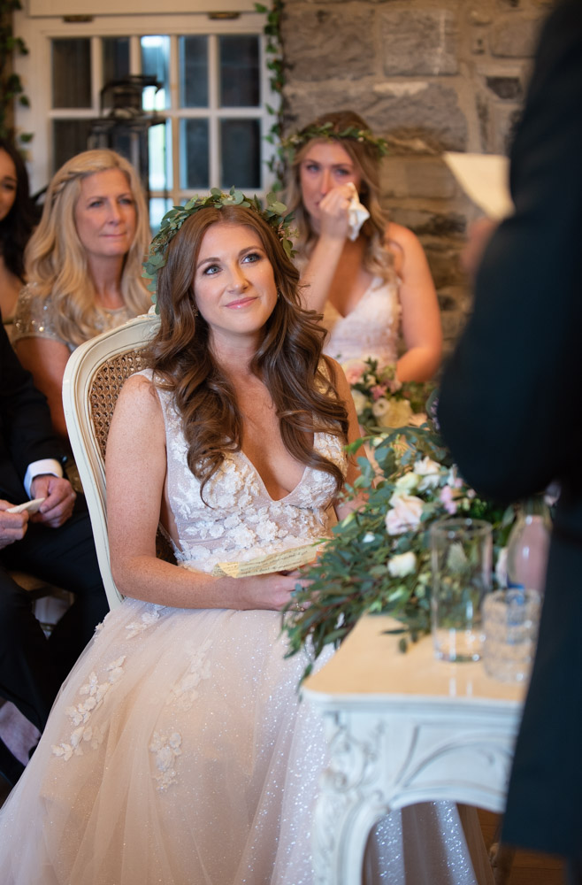 Bride smiling while looking and listening to Groom giving his speech