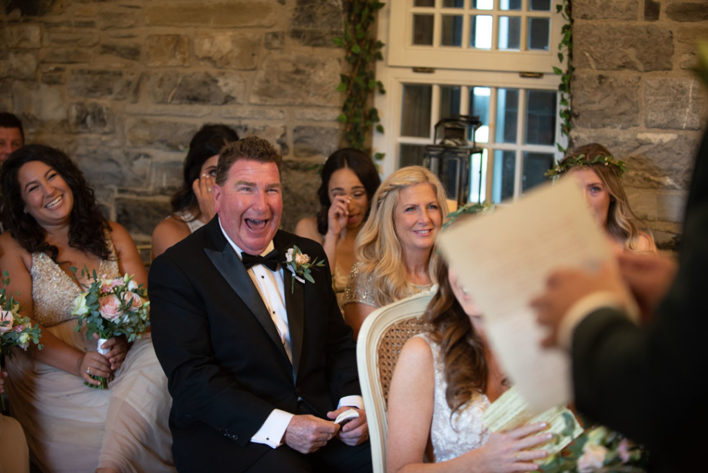 Father of the Bride laughing and looking at the Groom giving his speech