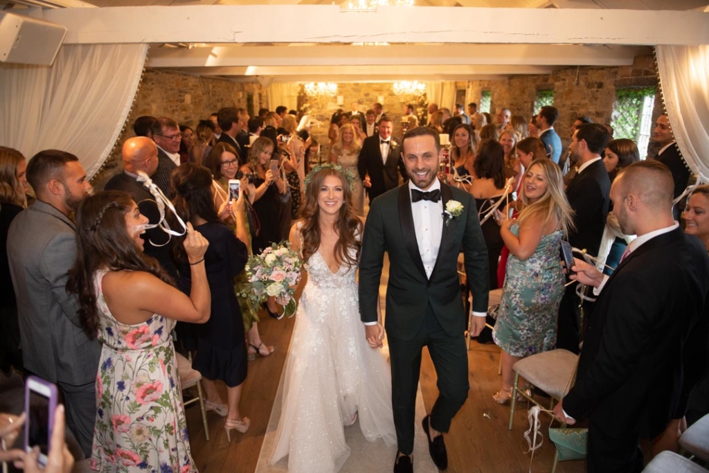 Bride and Groom walking down the aisle with gusts either side celebrating