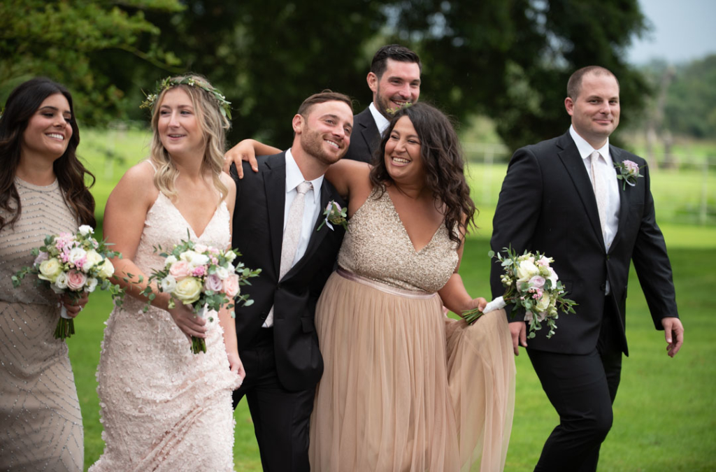 Bridal party walking and laughing together in the Ballymagarvey village grounds