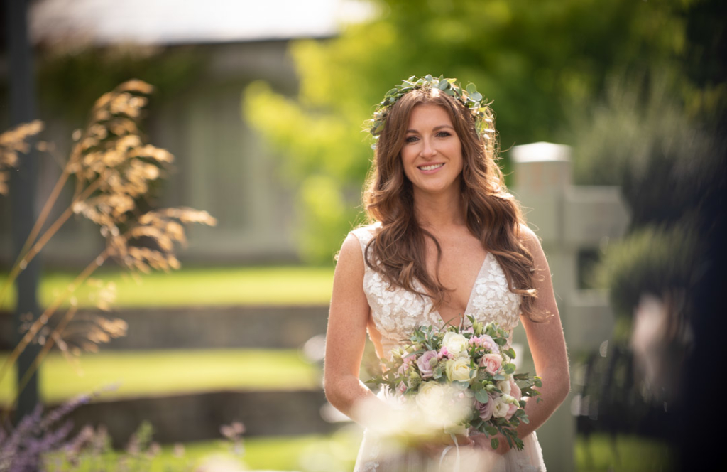 Bride holding her flowers with flower crown on her head surrounded by garden flowers