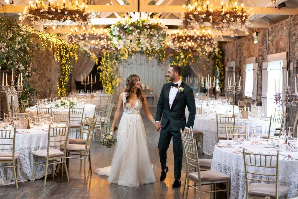 Bride and Groom holding hands walking through Ballymagarvey's reception room