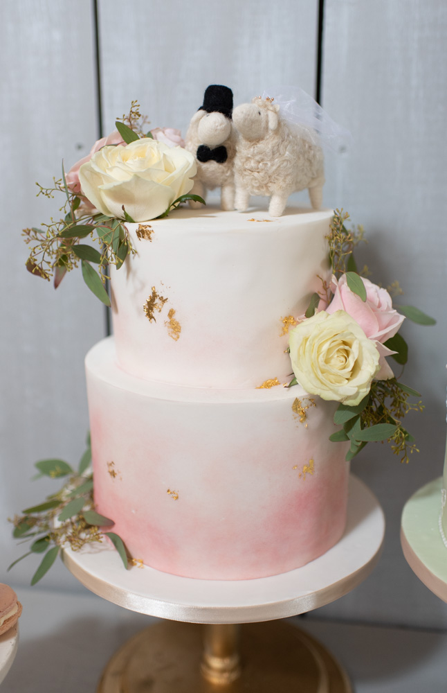 White and blush two tier wedding cake with flowers on it