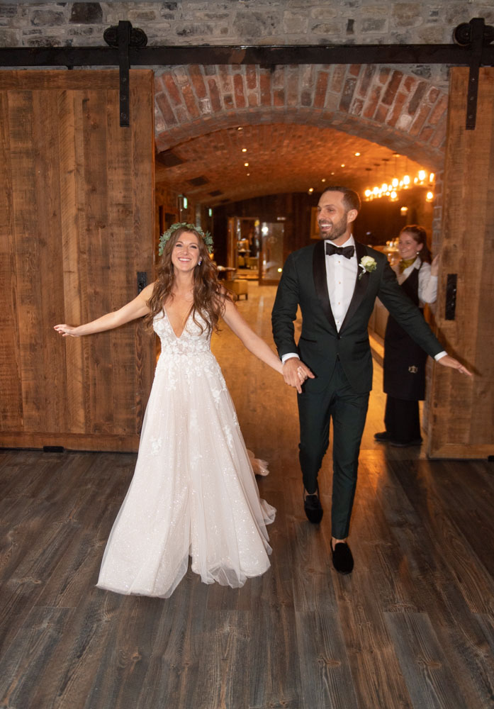 Bride and Groom smiling swinging their arms as they walk into their dinner reception