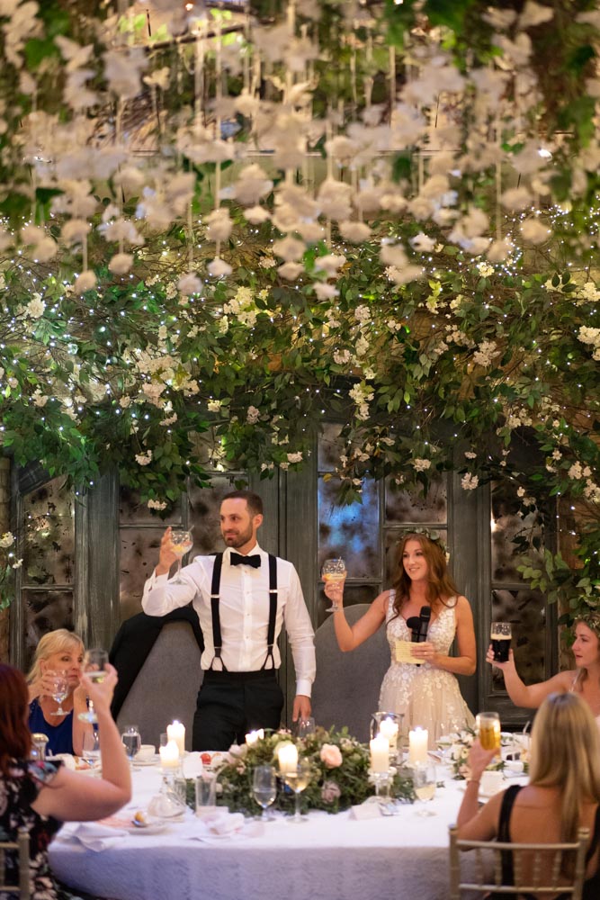 Bride and Groom standing while holding their wine glasses up at the top table at Ballymagarvey