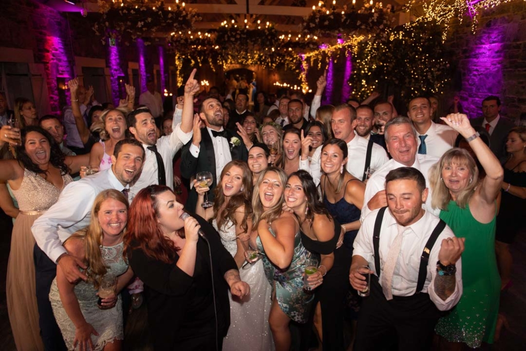 Wedding guests all on the dance floor cheering looking at camera