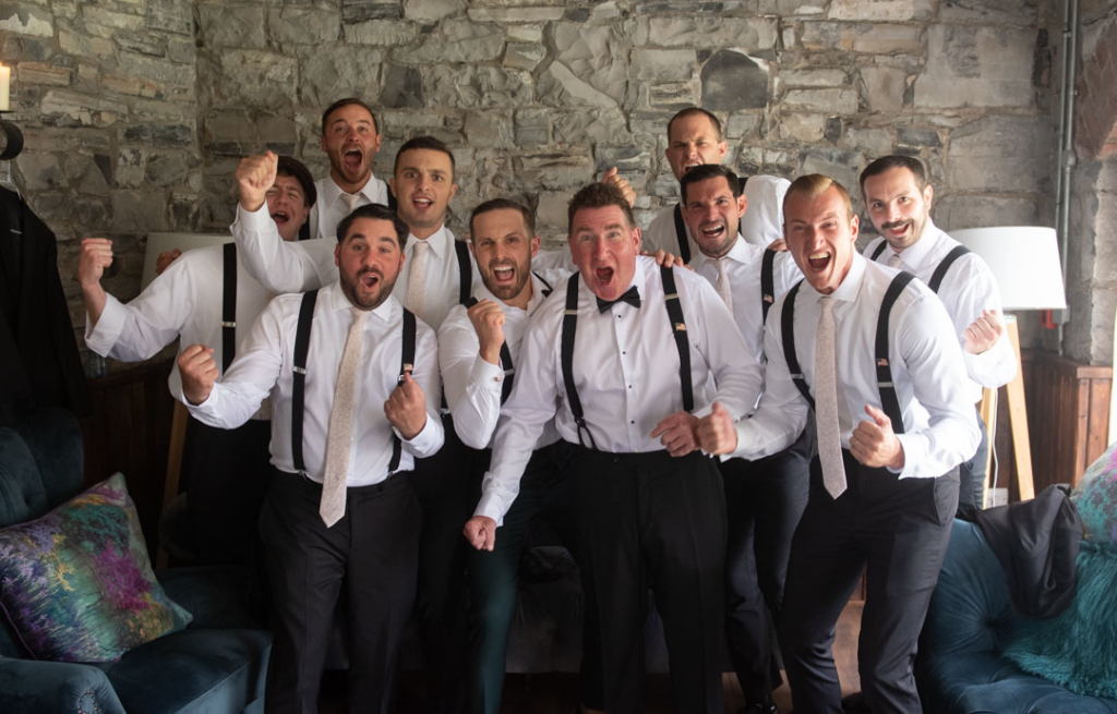 Groom and his groomsmen cheering looking at camera