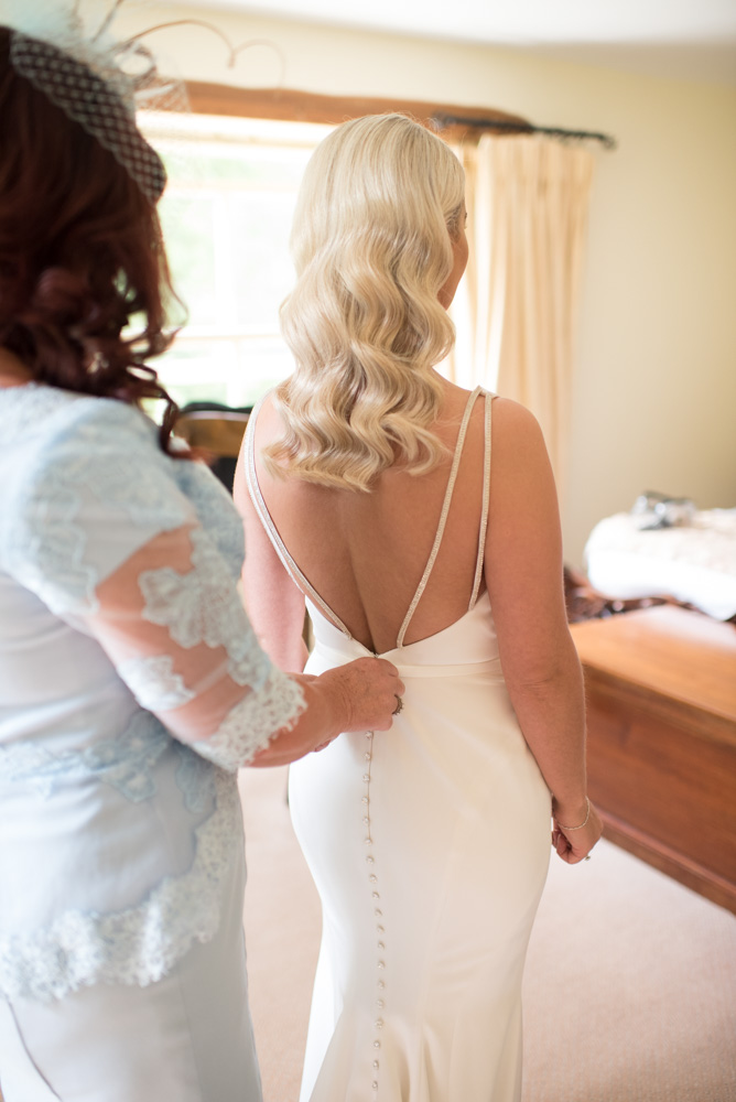 Mother of the bride zipping up dress on the Bride