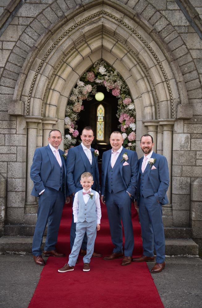 Groom and groomsman and pageboy standing outside at the front of the Church