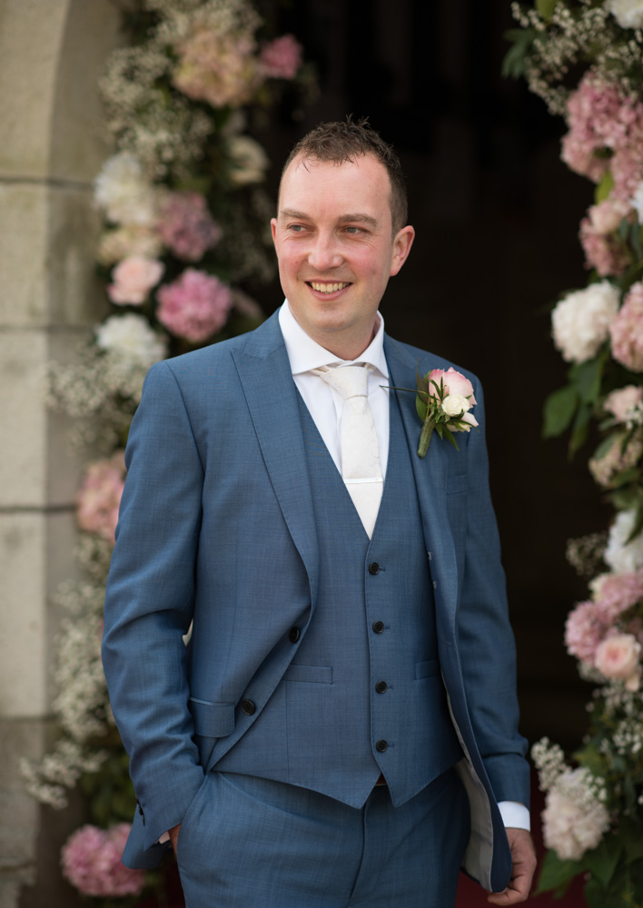 Groom wearing blue suit and white tie at the Church's door