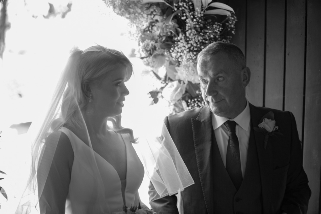 Father of the bride and bride looking at each other before they walk up the aisle
