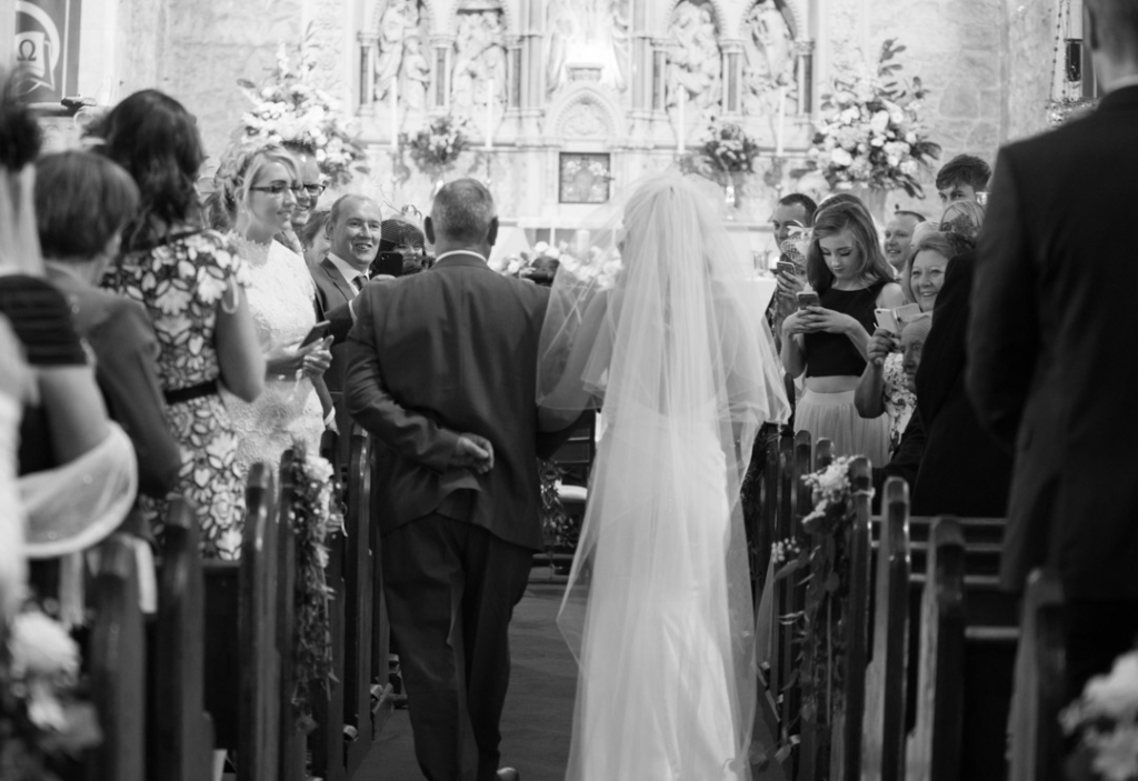 The back of the bride and her dad walking up the church aisle