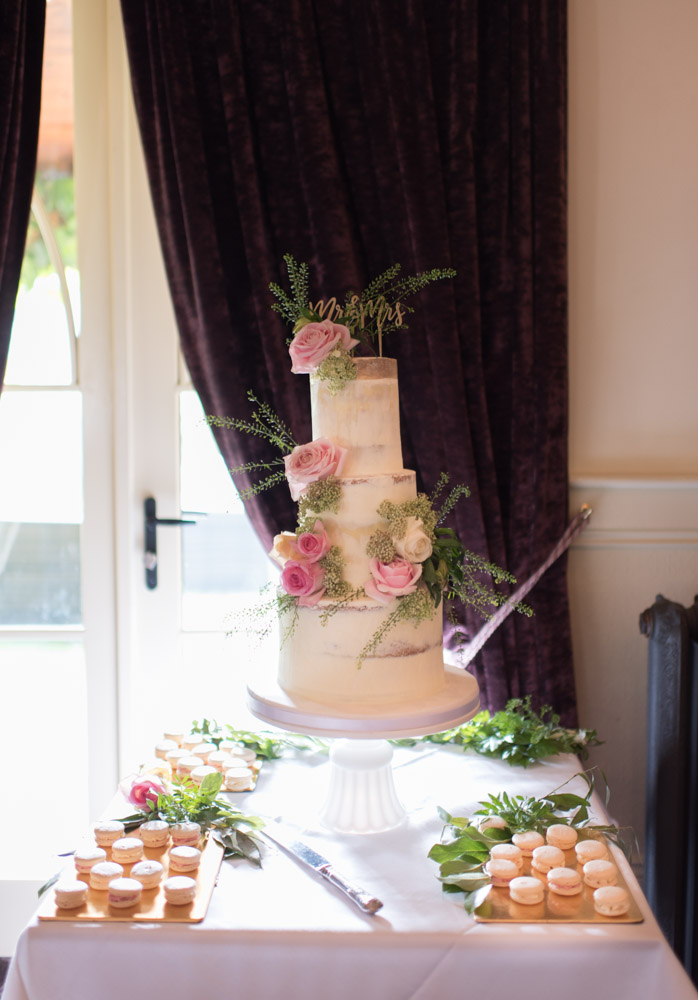 White naked wedding cake with pink rose flowers on top